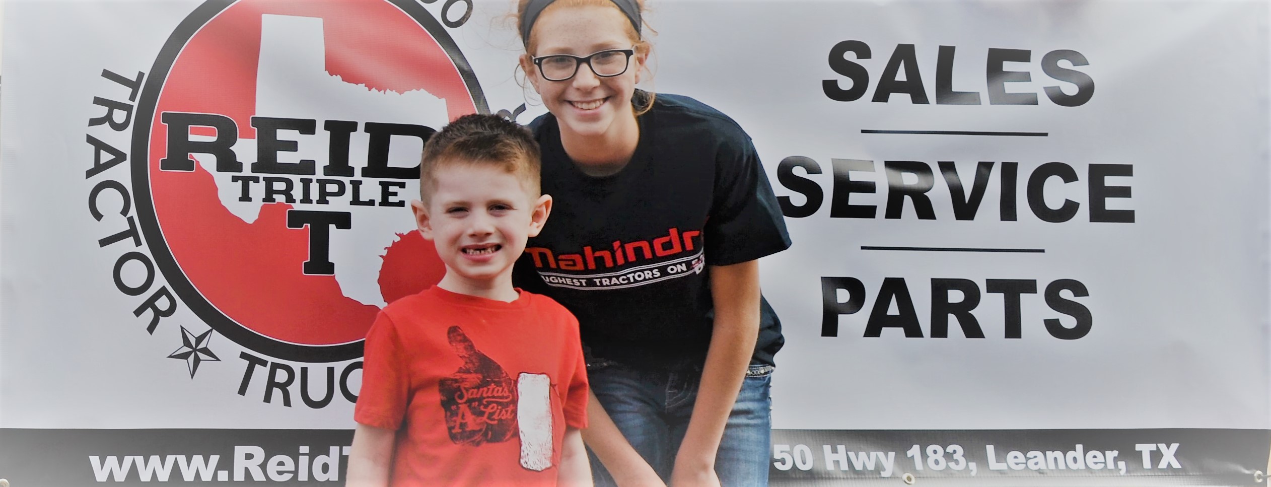 Reid Kids Austin and Jolie with the Reid's Triple T sign at the Liberty Hill Christmas Parade